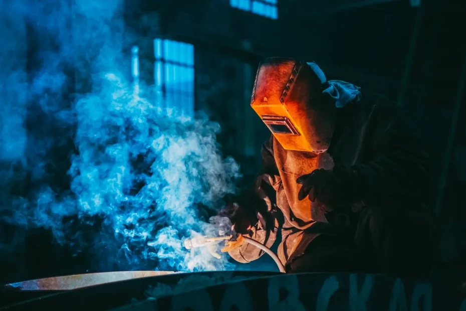 Soudeur au masque dans la fumée bleue de l'arc électrique