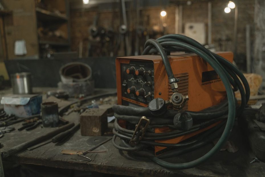 Poste à souder inverter orange sur un établi d’atelier, molettes de réglage et câbles