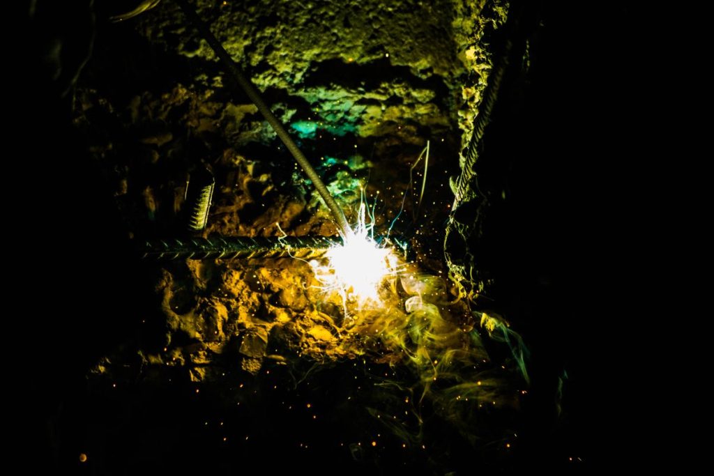 Arc de soudure éclatant sur une barre d'acier dans la pénombre
