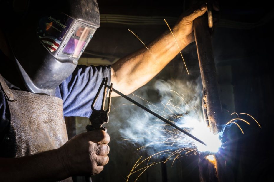 Soudeur soudant une pièce à l’électrode enrobée avec un porte-électrode, gerbe d’étincelles