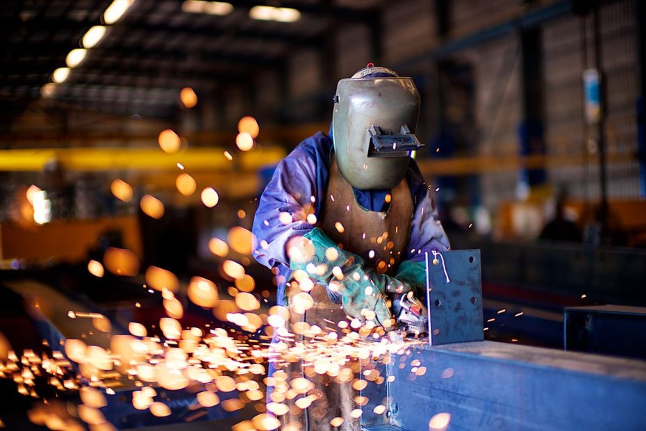 Soudeur au MIG dans un atelier, gerbe d’étincelles autour de la pièce